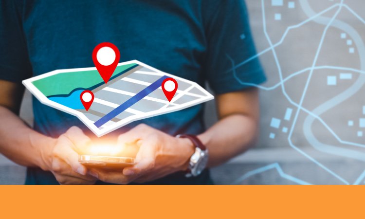 La imagen muestra una mano sosteniendo un teléfono inteligente con una pantalla luminosa. Encima del teléfono aparece una representación digital de un mapa con tres marcadores rojos de ubicación. El fondo incluye un diseño translúcido de un mapa con carreteras y edificios. Esta imagen ilustra el concepto de usar un teléfono inteligente para navegación o servicios basados en ubicación.